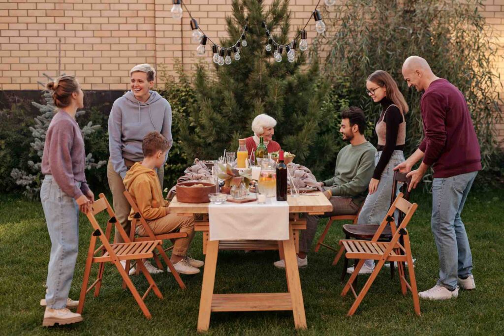 The image shows a garden scene where a family of seven people gather to celebrate with childrren and grandma.